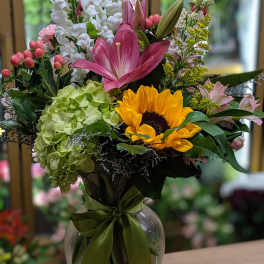 Mixed bouquet in a glass vase with sunflowers, lilies, and hydrangeas