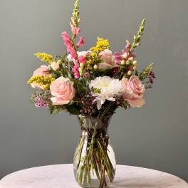 Pink roses and white blooms arranged in a clear glass vase