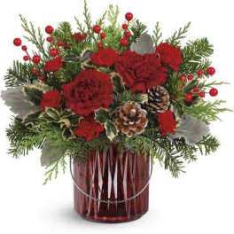 Red carnations in a red glass vase with pinecones and evergreen accents