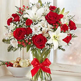 Bouquet of red roses and white lilies in a glass vase with a red ribbon