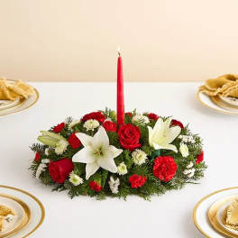 Red candle in a low floral centerpiece with white lilies and red roses