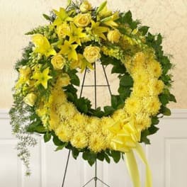 Yellow floral wreath on a black stand with a ribbon bow