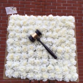White floral memorial display with a gavel on an easel
