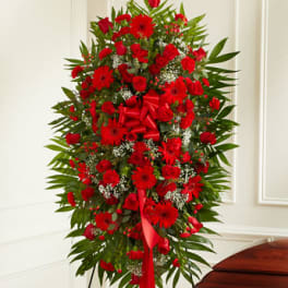 Tall standing spray of red flowers with a ribbon bow