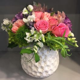 Pink and purple floral arrangement in a white textured vase