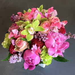 Pink and green mixed bouquet with roses, orchids, peonies, and hydrangea in a white vase