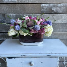 Mixed pink, purple, and white flower arrangement in a dark glass vase