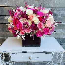 Pink and white rose arrangement in a square glass vase