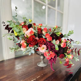Low floral centerpiece with red and pink blooms in a silver vase