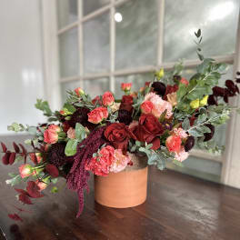 Red and pink rose arrangement in a terracotta vase