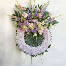 Large pastel floral wreath on an easel with pink, lavender, and green blooms