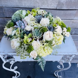 Low floral arrangement with white roses, succulents, and green orchids