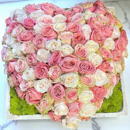 Heart-shaped arrangement of pink and white roses in a shallow box