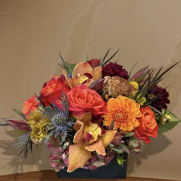 Colorful bouquet with roses, orchids, and dahlias in a dark vase