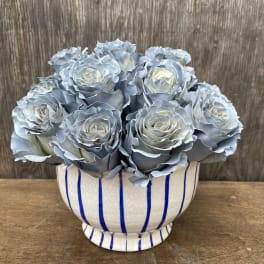 Blue-gray roses arranged in a striped ceramic vase