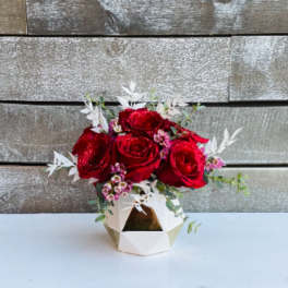 Red roses in a geometric white vase with small pink accents