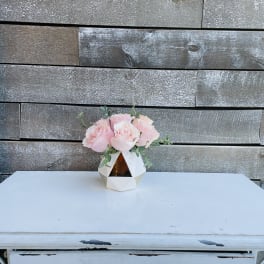 Pink roses in a geometric white vase on a table
