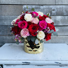 Bouquet of red, pink, and white roses in a gold vase