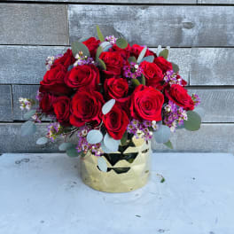 Bouquet of red roses with small purple filler flowers in a gold vase