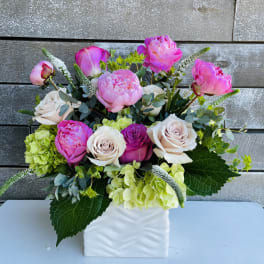 Pink and white flowers arranged in a white square vase
