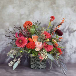 Bright mixed flower arrangement in a square textured vase