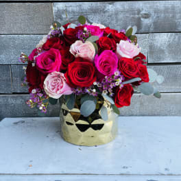 Bouquet of red, pink, and white roses in a gold vase
