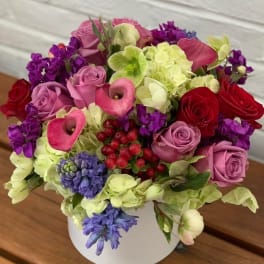 Mixed bouquet of pink roses, calla lilies, and hydrangeas in a white vase