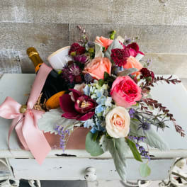 Bouquet of roses, orchids, and hydrangeas with a champagne bottle and candle