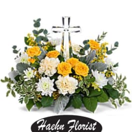 Yellow and white flower arrangement with a clear cross centerpiece