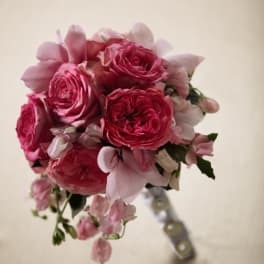 Compact bouquet of bright and pale pink roses and flowers with a wrapped handle