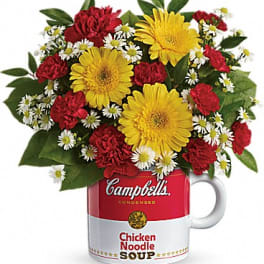 Bouquet of yellow gerbera daisies and red carnations in a Campbell's soup mug