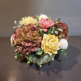 Artificial floral arrangement in a low ceramic bowl with pink, yellow, and white blooms