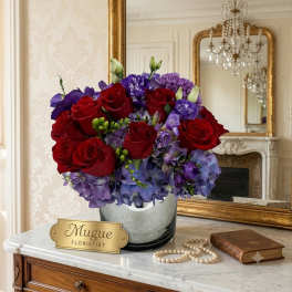 Red roses and purple flowers arranged in a silver vase
