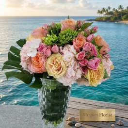 Pastel rose bouquet in a clear glass vase by the water