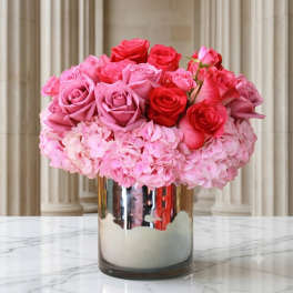 Pink and red roses arranged in a mirrored vase