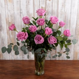 Tall glass vase of lavender roses with cascading eucalyptus stems