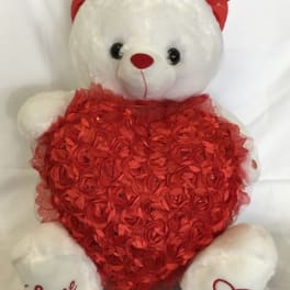 White teddy bear with red ears holding a large red rosette heart pillow