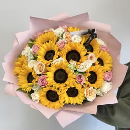 Bouquet of sunflowers and pastel roses wrapped in pink paper