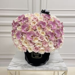 Large bouquet of pink and white roses with purple orchids in a black hat box