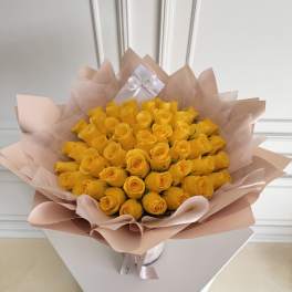 Bouquet of yellow roses wrapped in pale pink paper