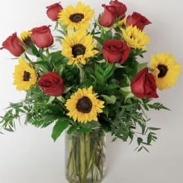 Arrangement of red roses and yellow sunflowers in a clear glass vase
