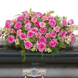 Pink rose and carnation casket spray arranged on a dark metal casket