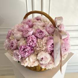 Pink peonies in a wicker basket with a ribbon bow