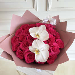 Bouquet of hot pink roses with two white orchids in pink wrapping