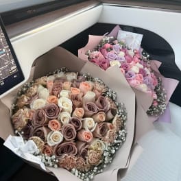 Two bouquets of pastel roses wrapped in paper on a car seat