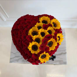Heart-shaped arrangement of red roses with yellow sunflowers