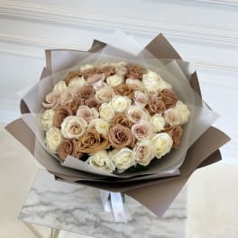 Bouquet of cream and blush roses wrapped in brown and white paper