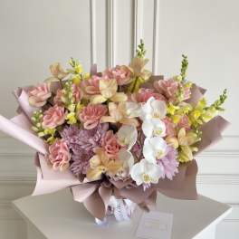Pastel bouquet with pink roses, orchids, and lavender mums wrapped in blush paper