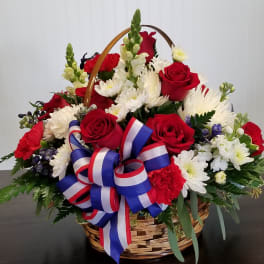 Basket arrangement of red roses and white daisies with a red-white-blue ribbon