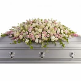 Pastel floral casket spray on a gray coffin